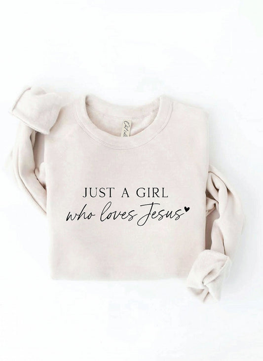 Beige sweatshirt with 'Just a Girl who loves Jesus' text on a white background. Oat Collective, super soft. 
